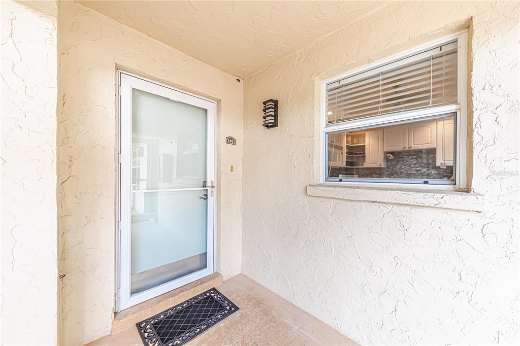 A front entrance with a white storm door, a window, and a small welcome mat — 616 FLAMINGO DRIVE UNIT 102, VENICE, FL