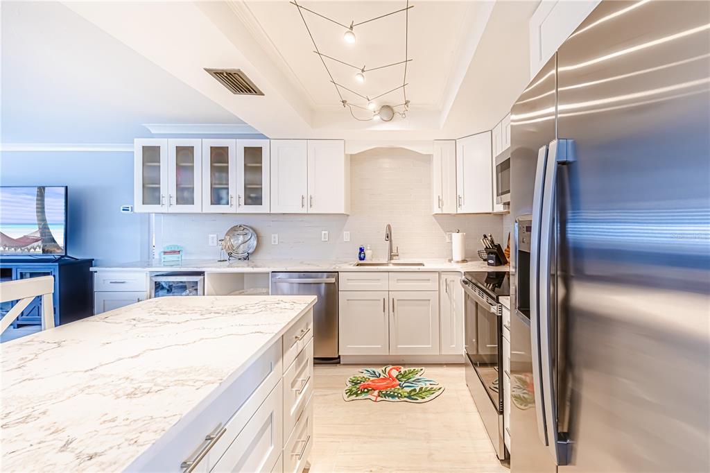 A modern kitchen features white cabinets, marble-patterned countertops, stainless steel appliances, and a central island — 616 FLAMINGO DRIVE UNIT 102, VENICE, FL