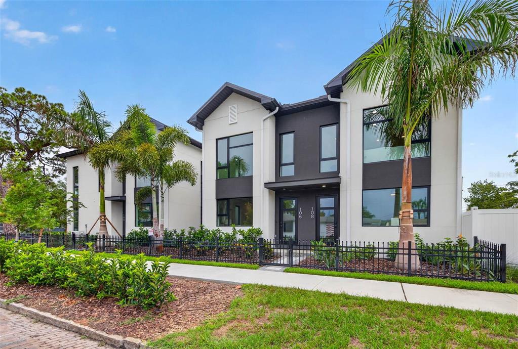 A modern two-story duplex with white and dark gray exterior walls behind a black fence — 100 36TH STREET N, ST PETERSBURG, FL