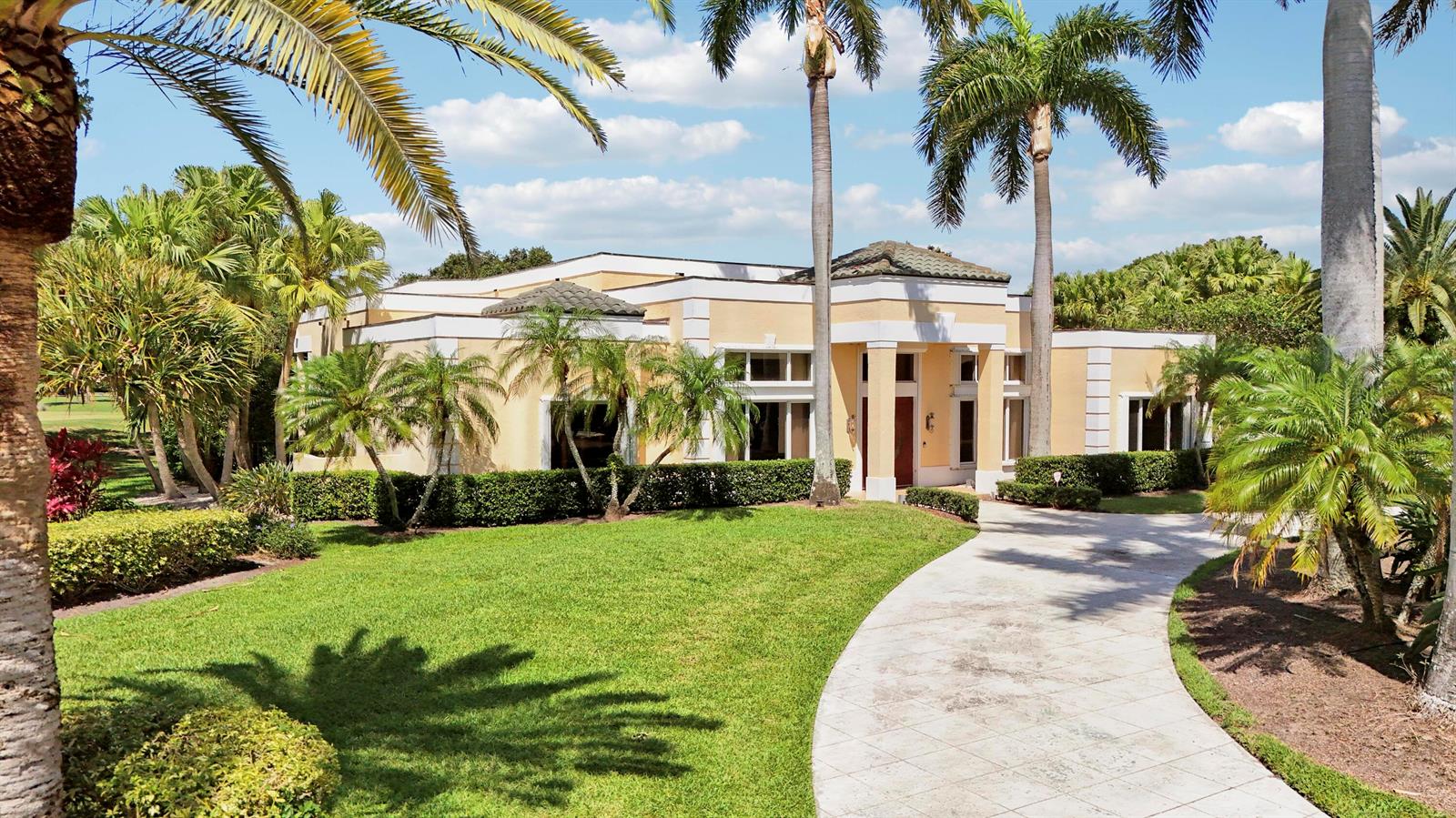 A single-story tan house with a paved driveway and palm trees in a sunny yard — 171 Spyglass Lane, Jupiter FL 33477, JUPITER, FL