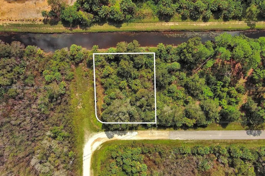 An aerial view shows a rectangular plot of land outlined in white near a canal — 862 ASHLAND STREET E, LEHIGH ACRES, FL