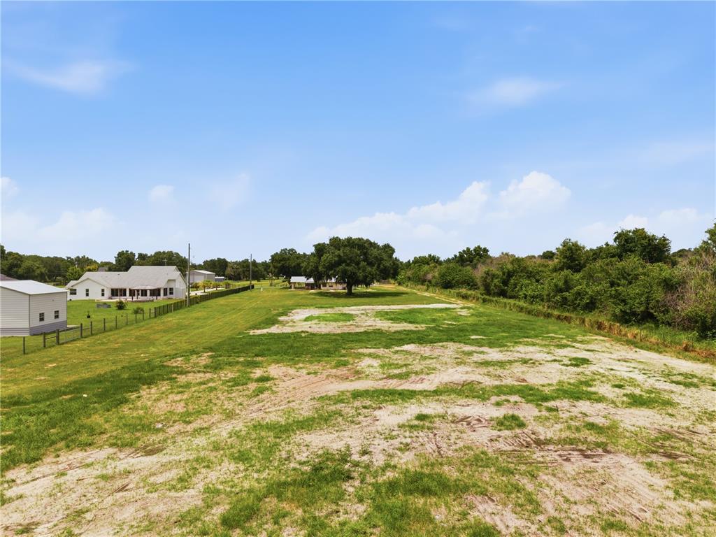 A large, mostly cleared grassy lot with a few trees and neighboring houses in view — PARKWAY AVENUE, ST CLOUD, FL