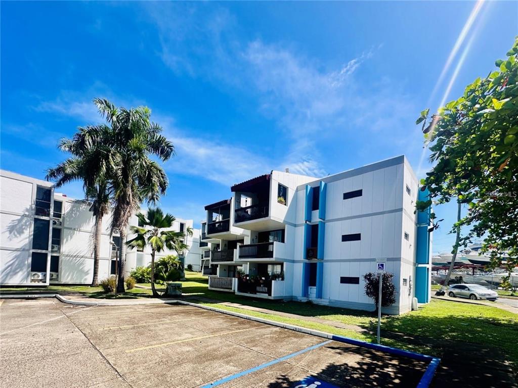 A multi-story apartment building with balconies and a parking lot under a blue sky — Villa Marina Condo VILLA MARINA AVE. UNIT D201, FAJARDO, PR