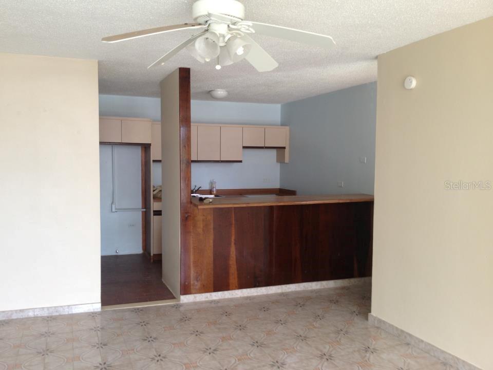 A kitchen with wood-paneled cabinetry and a breakfast bar opens into a tiled living area — Villa Marina Condo VILLA MARINA AVE. UNIT D201, FAJARDO, PR