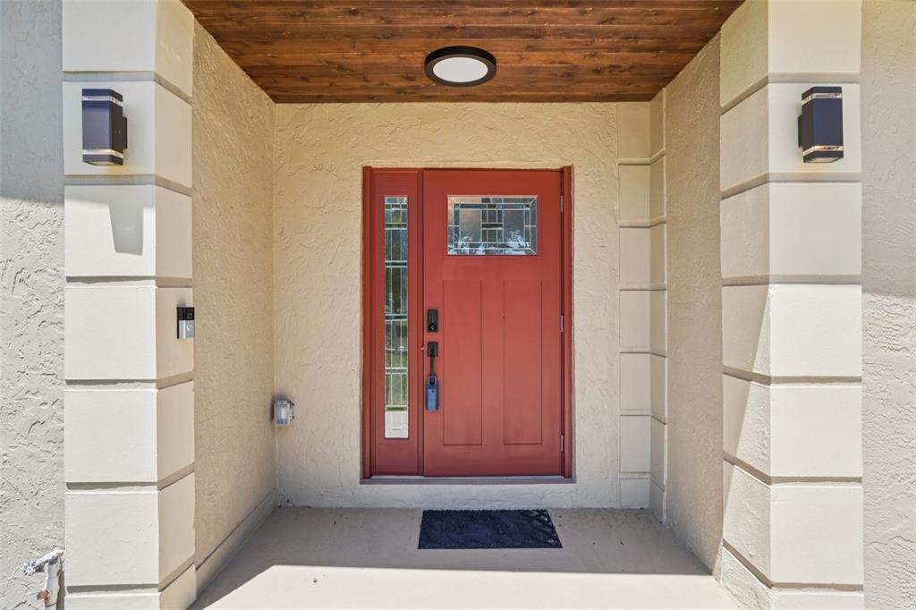 A red front door with a sidelight is framed by two white stucco columns — 3123 W LA SALLE STREET, TAMPA, FL