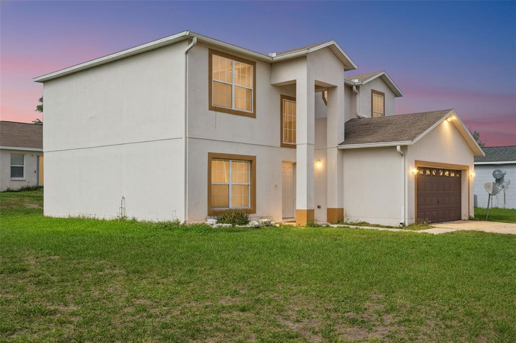 A two-story house with a white stucco exterior, brown trim, and an attached garage — 342 PUFFER COURT, POINCIANA, FL
