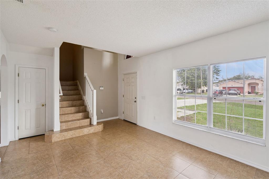 An entryway with tiled floors, a staircase with a white railing, and a large window — 342 PUFFER COURT, POINCIANA, FL