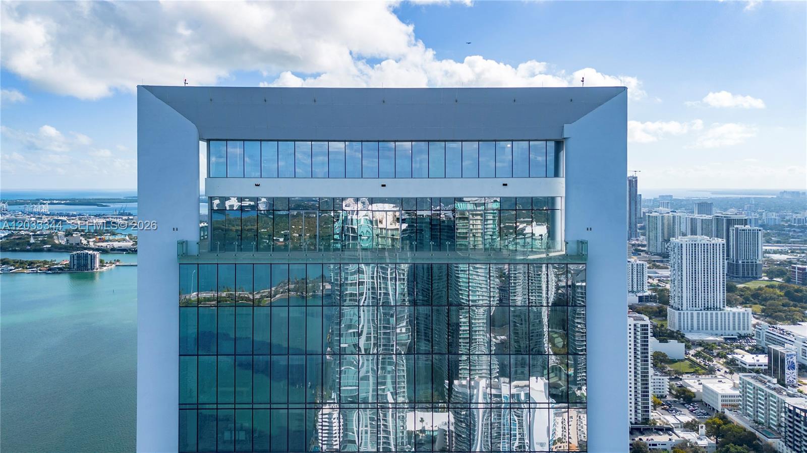 An exterior view of a high-rise building with a glass facade and a balcony — 700 NE 26th Ter # 01, Miami FL 33137, MIAMI, FL