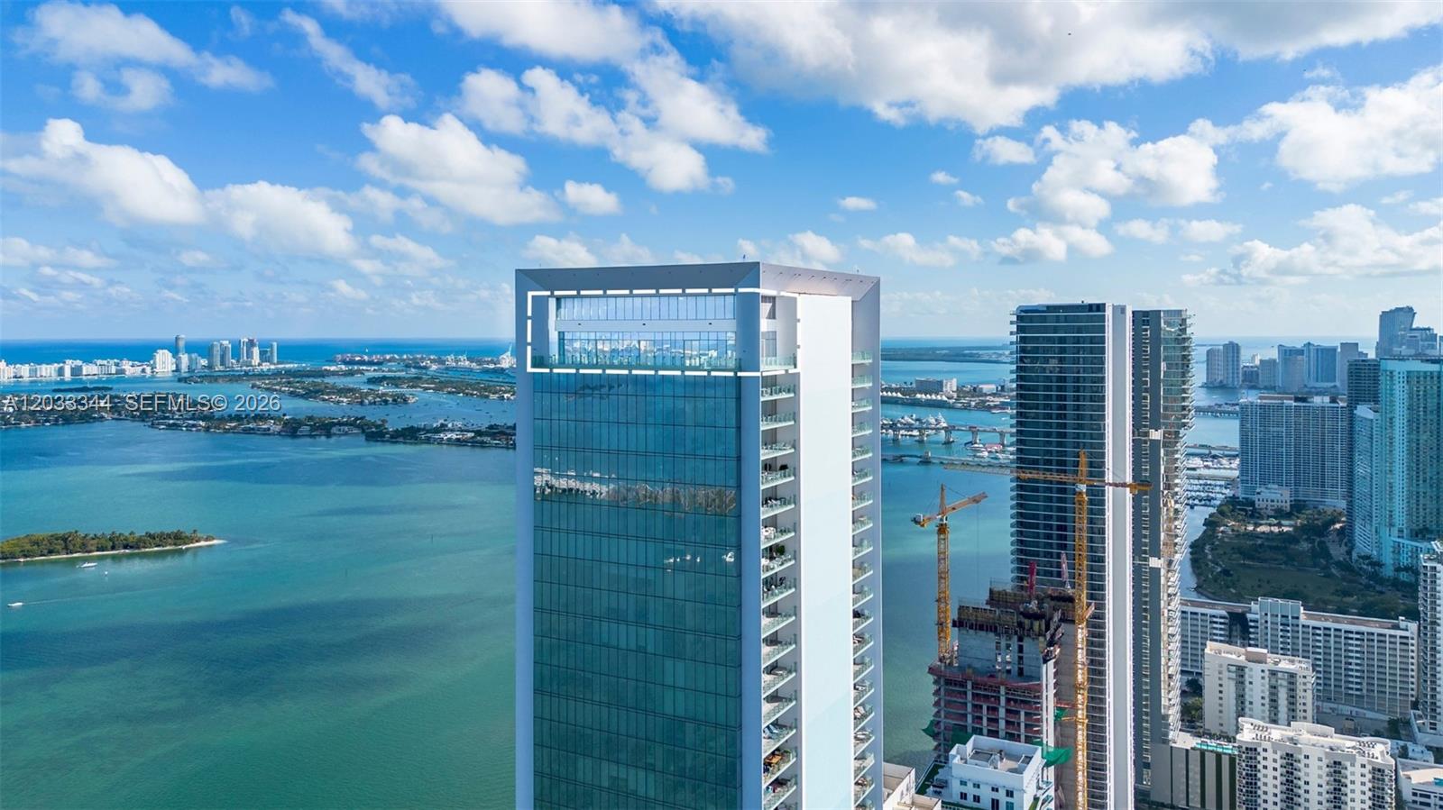 An aerial view shows a modern glass skyscraper with a prominent rooftop terrace — 700 NE 26th Ter # 01, Miami FL 33137, MIAMI, FL
