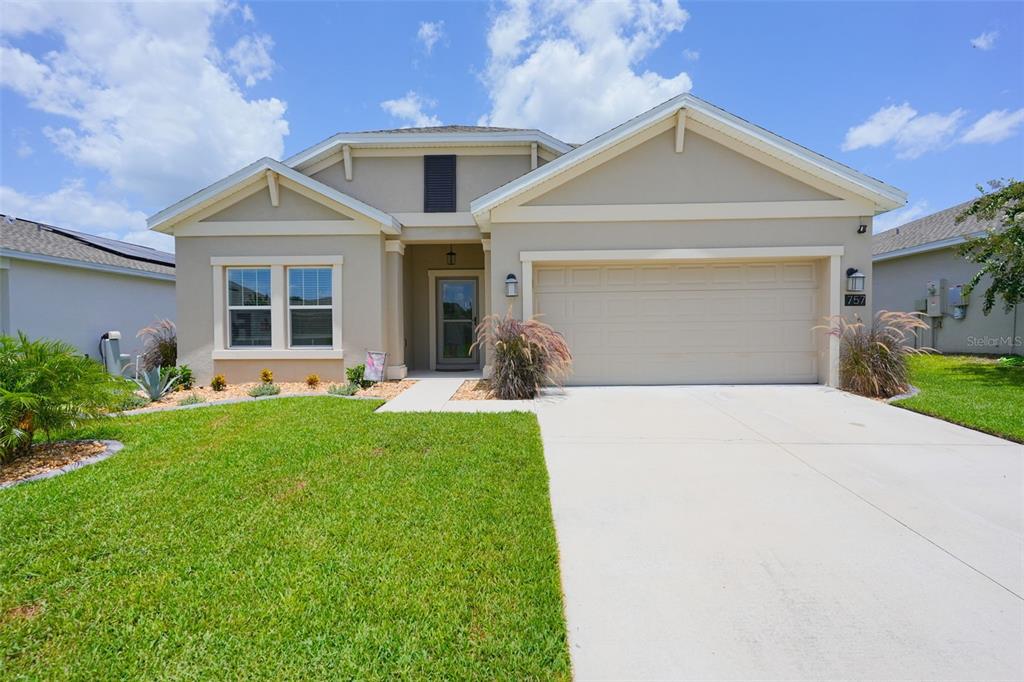 A single-story suburban house with a beige stucco exterior, a two-car garage, and landscaping — 757 CITRUS RESERVE BOULEVARD, DAVENPORT, FL
