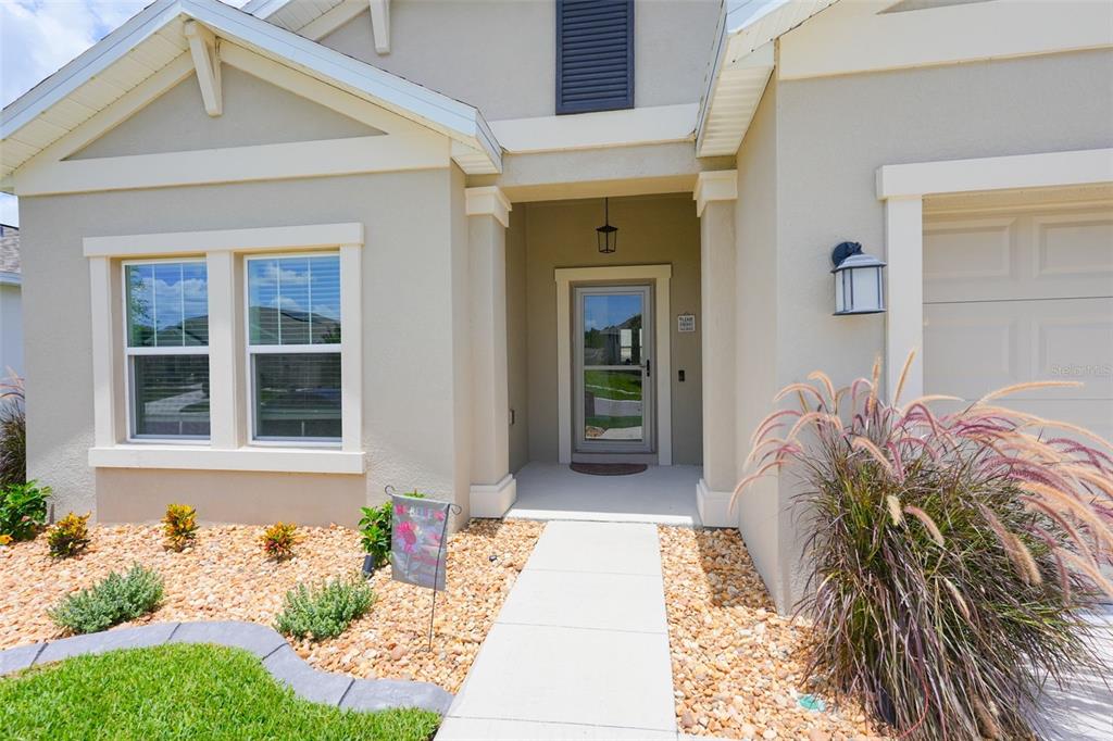 The exterior of a beige house features a front walkway, a glass storm door, and landscaping — 757 CITRUS RESERVE BOULEVARD, DAVENPORT, FL