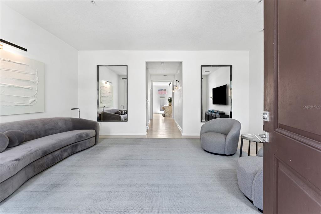 A minimalist living room features a gray sofa, two armchairs, and two large wall mirrors — 771 LAKE BALDWIN LANE, ORLANDO, FL