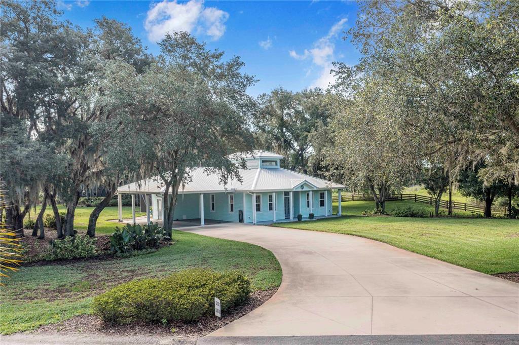 A light blue house with a metal roof sits at the end of a driveway — 2424 BURNS AVENUE, LAKE WALES, FL