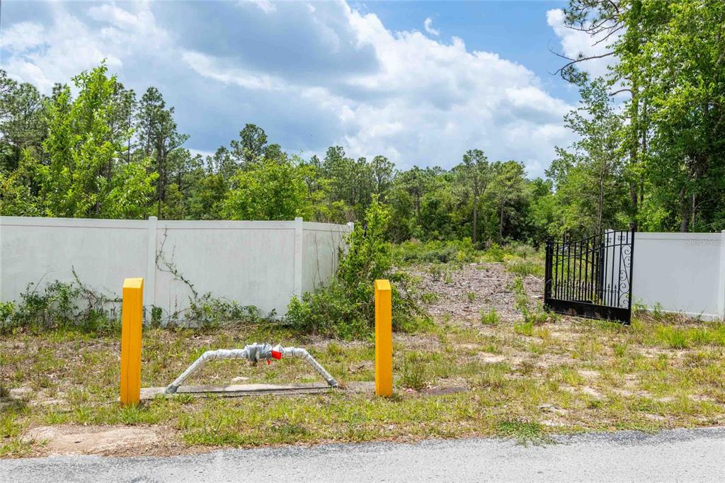 A vacant lot features a white vinyl fence, a black metal gate, and a fire hydrant — 15022 GAR STREET, SPRING HILL, FL