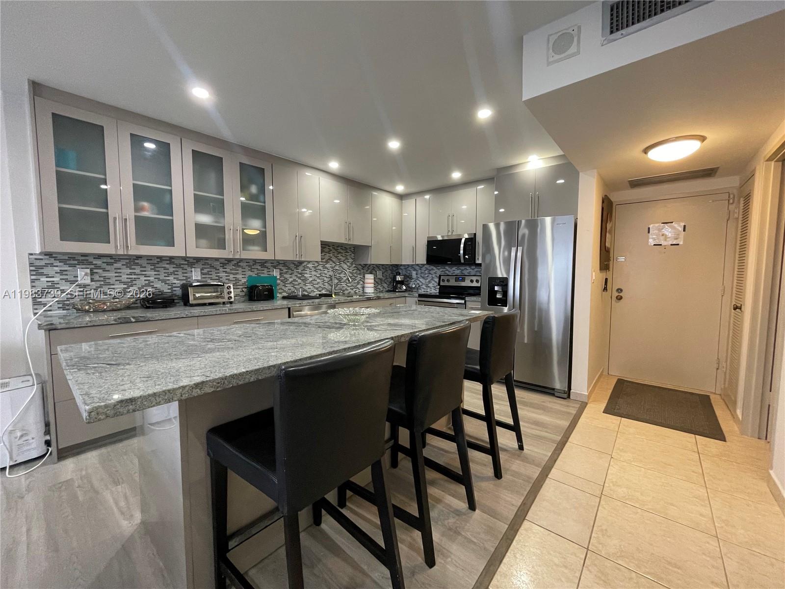 A modern kitchen features gray cabinetry, granite countertops, a breakfast bar, and stainless steel appliances — 3725 S Ocean Dr # 911, Hollywood FL 33019, HOLLYWOOD, FL