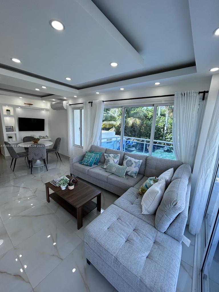 A living room features a gray sectional sofa, a coffee table, and a dining area — 2222 Carretera Sanchez # 202, CA 91000, CA