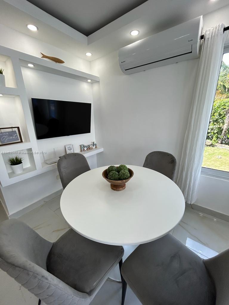 A dining area features a round white table, four gray chairs, and a wall-mounted television — 2222 Carretera Sanchez # 202, CA 91000, CA