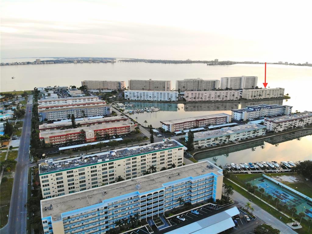 An aerial view shows multiple multi-story apartment buildings surrounding a marina and a large bay — 6075 SHORE BOULEVARD S UNIT 606, GULFPORT, FL