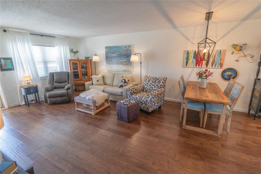 A living and dining area with hardwood floors, a beige sofa, and a wooden table — 6075 SHORE BOULEVARD S UNIT 606, GULFPORT, FL