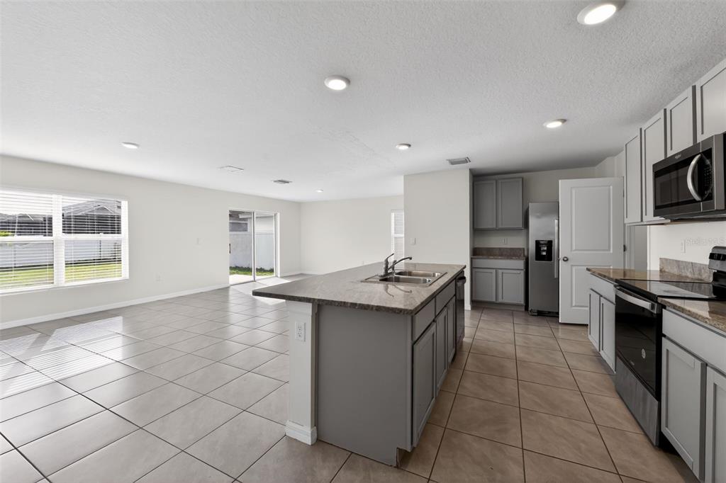 A kitchen with a gray island and cabinets, stainless steel appliances, and tile flooring — 439 SUNLIT CORAL STREET, RUSKIN, FL