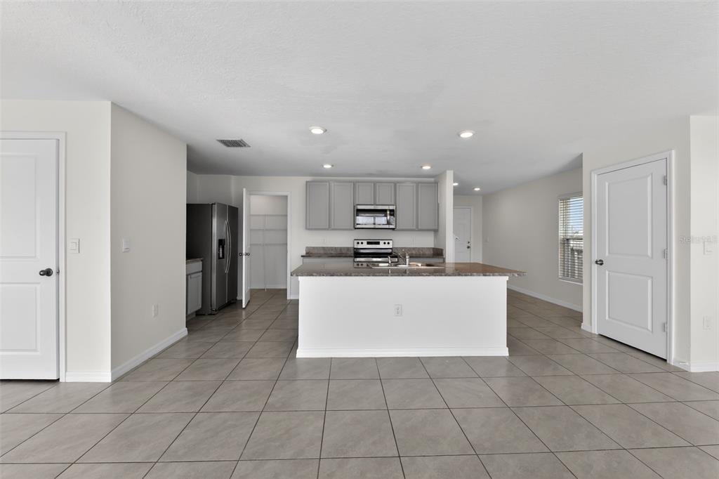 A kitchen with gray cabinets, stainless steel appliances, a center island, and light tile flooring — 439 SUNLIT CORAL STREET, RUSKIN, FL