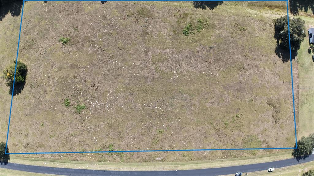 An aerial view shows a rectangular, grassy vacant lot bordered by a paved road — NW 54TH LOOP LOT 6, OCALA, FL