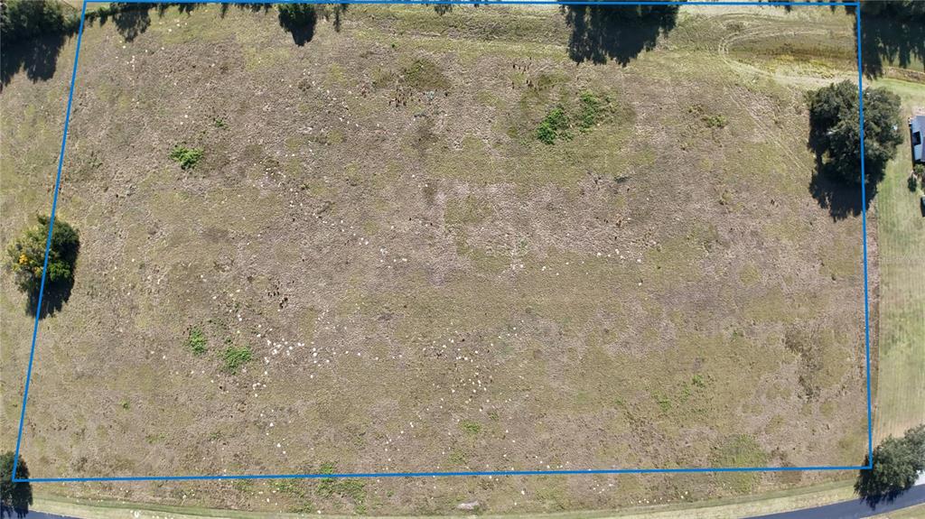 An aerial view shows a large, rectangular, undeveloped grassy lot outlined in blue — NW 54TH LOOP LOT 6, OCALA, FL