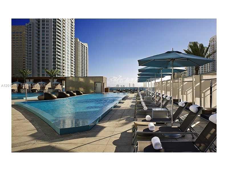 An outdoor swimming pool with lounge chairs and umbrellas on a high-rise building terrace — 200 Biscayne Boulevard Way # 4904, Miami FL 33131, MIAMI, FL
