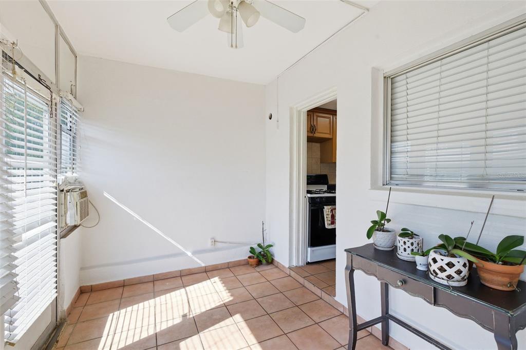 A sunroom with tiled floors, a ceiling fan, and a view into a kitchen — 5876 21ST STREET N UNIT 5, ST PETERSBURG, FL
