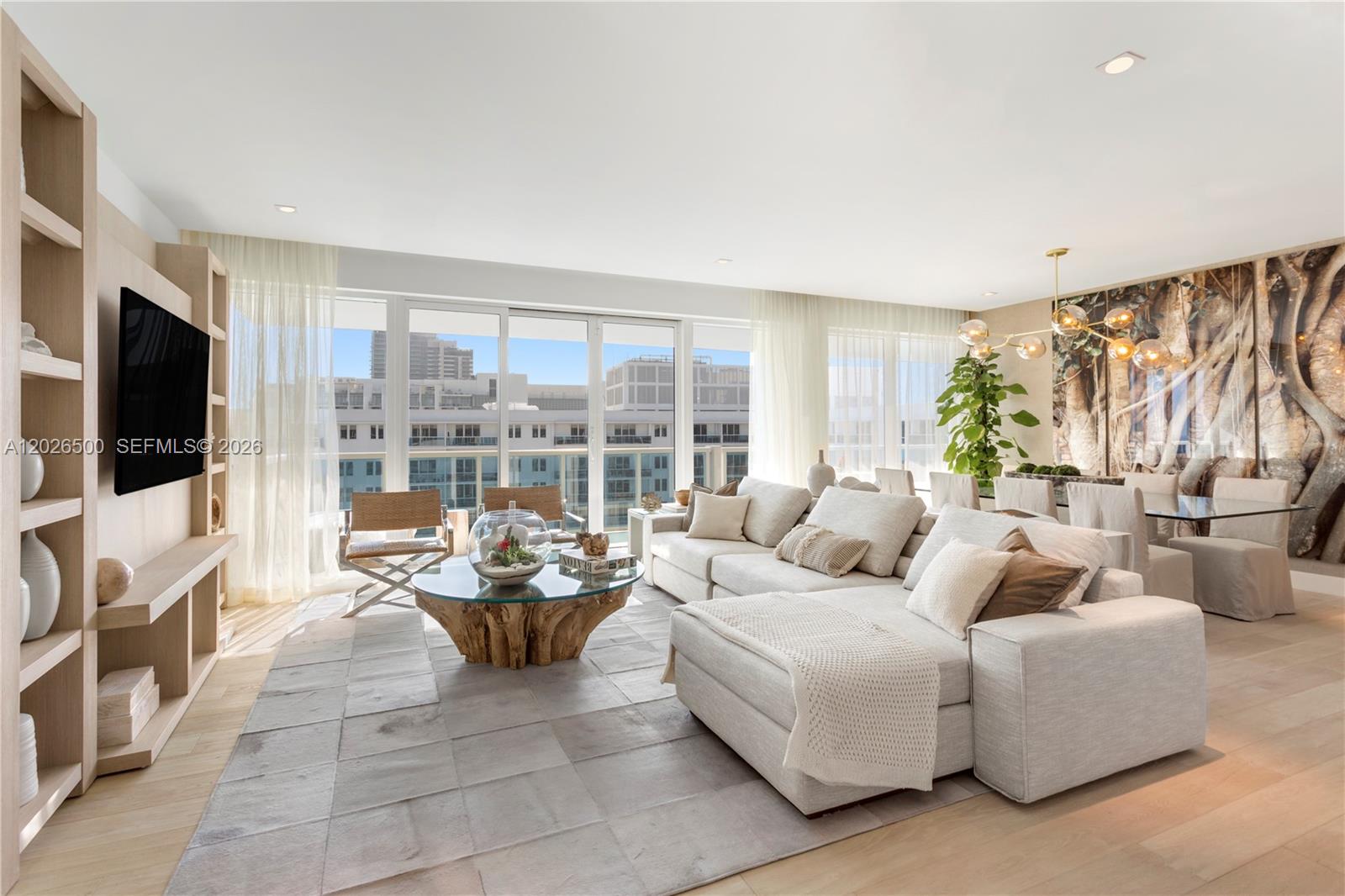 A bright, modern living room features a large sectional sofa, wood-base coffee table, and shelving — 102 24th St # 1706, Miami Beach FL 33139, MIAMI BEACH, FL