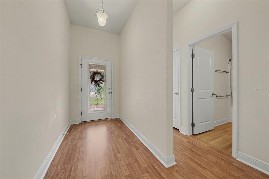 An entryway features wood-look flooring, a glass-paneled front door, and a doorway leading to a bathroom — 567 CORAL TRACE BOULEVARD, EDGEWATER, FL