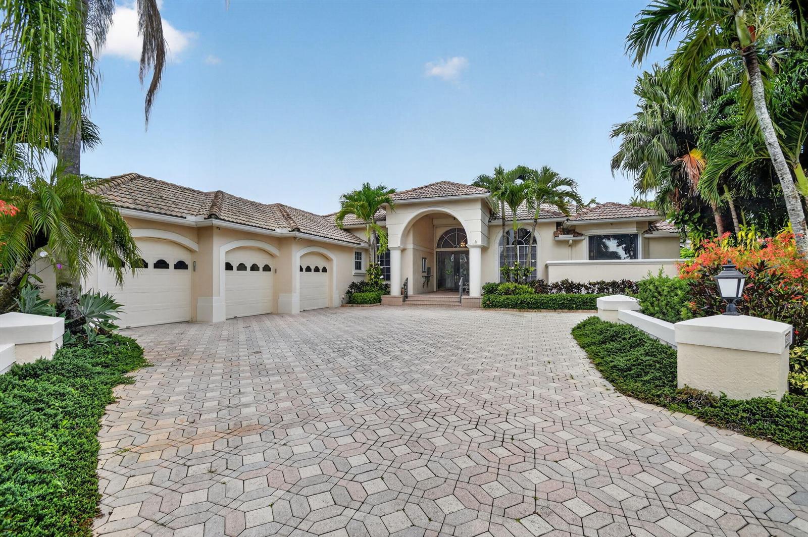 A beige single-story house with a three-car garage and a paved driveway surrounded by palms — 4936 Exeter Estate Lane, Lake Worth FL 33449, LAKE WORTH, FL