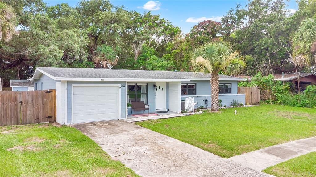 A single-story house with a light blue exterior, a white garage door, and a concrete driveway — 1717 WHITE STREET, TITUSVILLE, FL