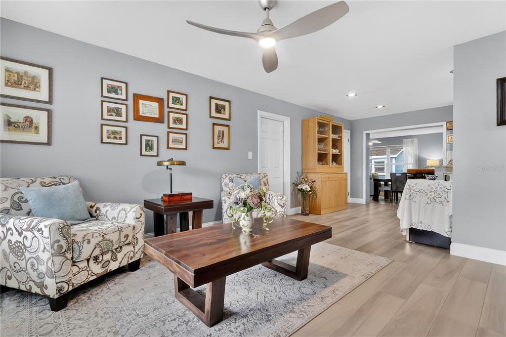 A living room features a patterned armchair, a wooden coffee table, and a ceiling fan — 1717 WHITE STREET, TITUSVILLE, FL