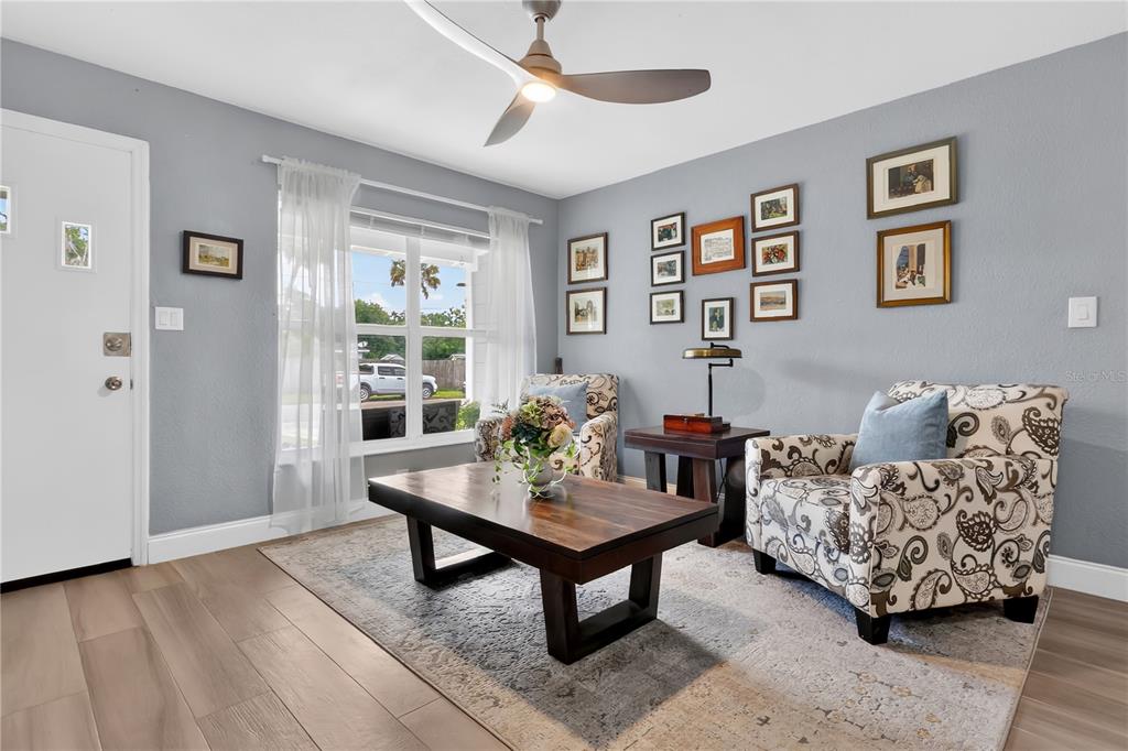 A living room features two patterned armchairs, a wooden coffee table, and a gallery wall — 1717 WHITE STREET, TITUSVILLE, FL