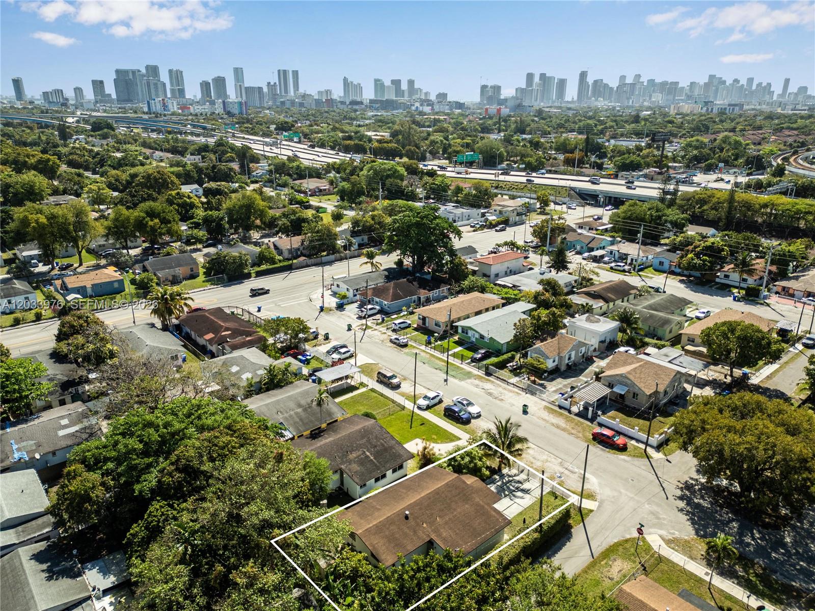 An aerial view shows a residential neighborhood with a highlighted single-story house and skyline — 1243 NW 42nd St, Miami FL 33142, MIAMI, FL
