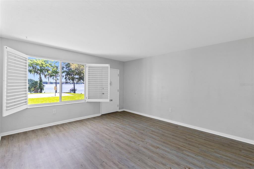 An empty room with light gray walls, wood-look flooring, and a window overlooking a lake — 1140 S ORLANDO AVENUE UNIT H3, MAITLAND, FL