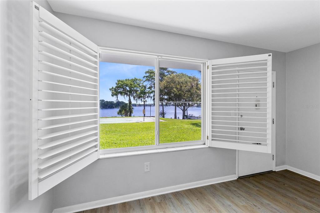 A room with light gray walls, wood-look flooring, and a window overlooking a lake — 1140 S ORLANDO AVENUE UNIT H3, MAITLAND, FL