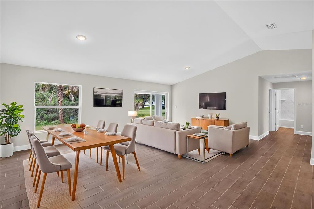 An open-concept living and dining area features light-colored walls, wood-look tile flooring, and large windows — 19112 RUSKIN AVENUE, PORT CHARLOTTE, FL