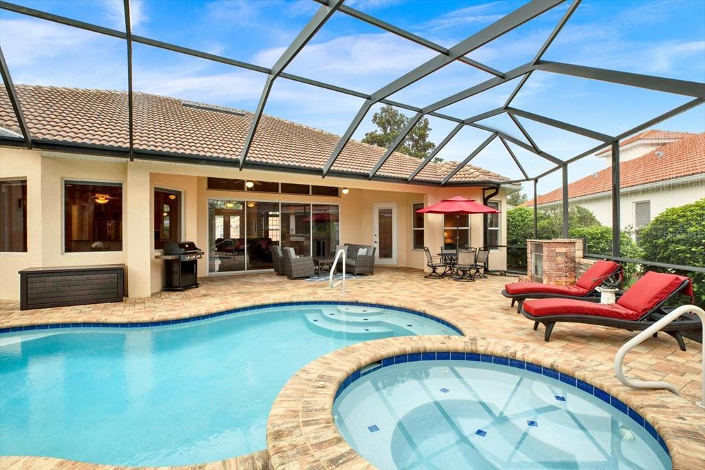 A screened-in patio features a swimming pool, a hot tub, and red lounge chairs — 9004 JERICHO ROAD, WEEKI WACHEE, FL