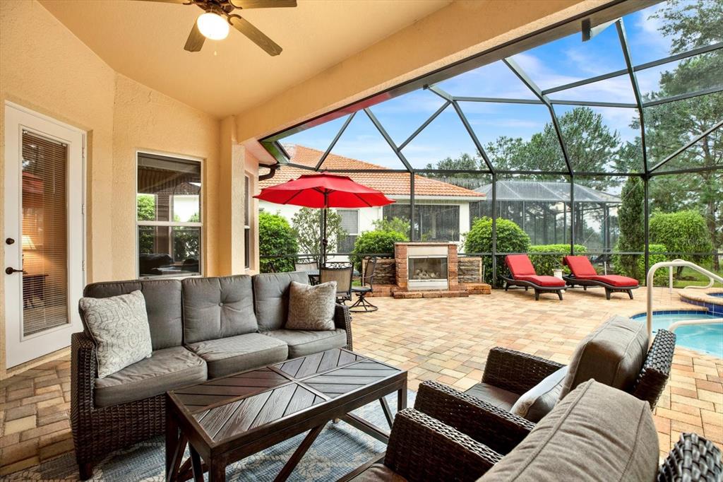 A covered patio features outdoor furniture, a fireplace, and a screened-in pool area — 9004 JERICHO ROAD, WEEKI WACHEE, FL