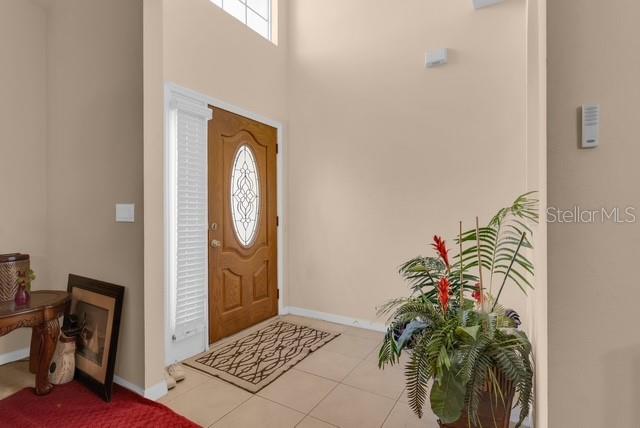 A high-ceilinged entryway features a wooden front door, a tiled floor, and a potted plant — 5120 SHALE RIDGE TRAIL, ORLANDO, FL