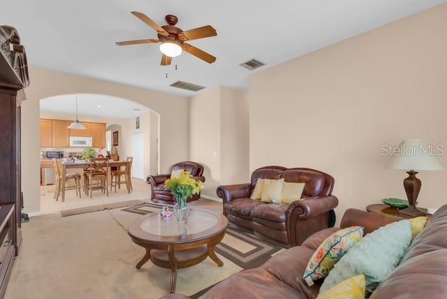 A living room with brown leather furniture, a ceiling fan, and an open kitchen view — 5120 SHALE RIDGE TRAIL, ORLANDO, FL