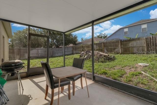 A screened-in patio features a small dining set and a grill overlooking a fenced backyard — 5120 SHALE RIDGE TRAIL, ORLANDO, FL