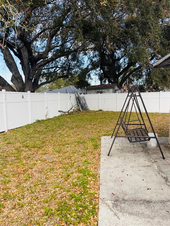 A backyard features a white vinyl fence, a metal swing, and a concrete patio area — 2910 VIENNA LANE, KISSIMMEE, FL