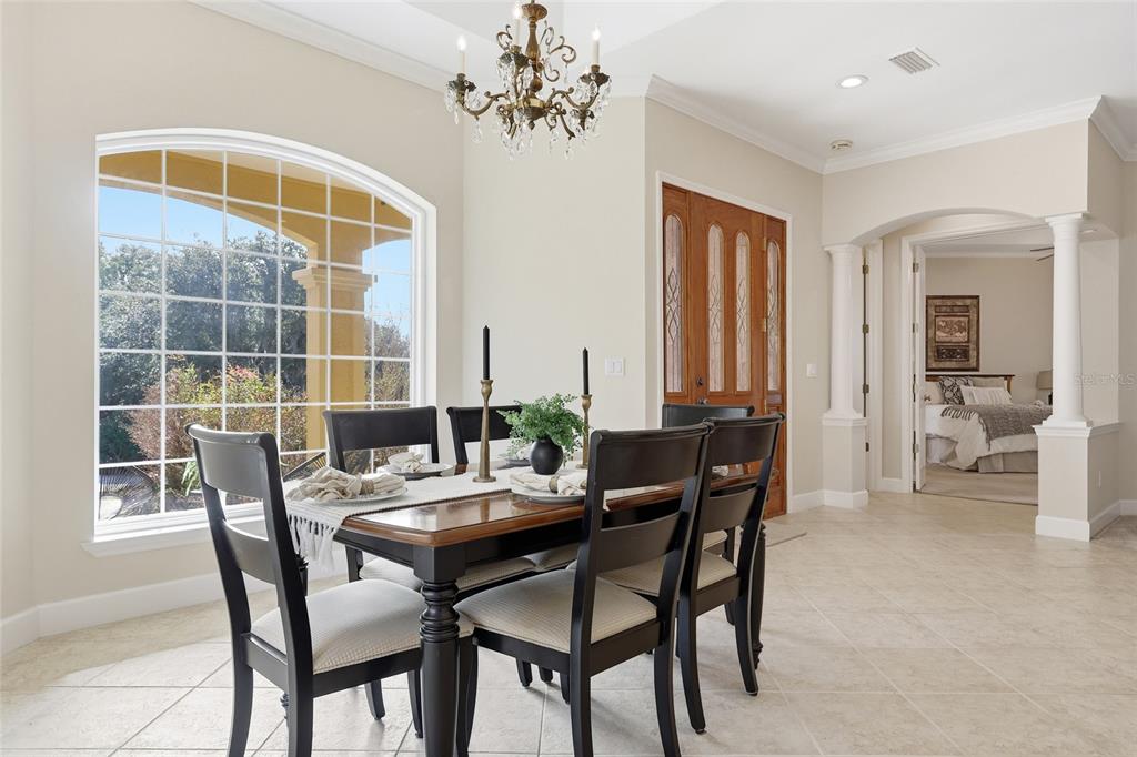 A dining area features a dark wood table, chandelier, arched window, and tiled flooring — 18604 NW 262 AVENUE, ALACHUA, FL