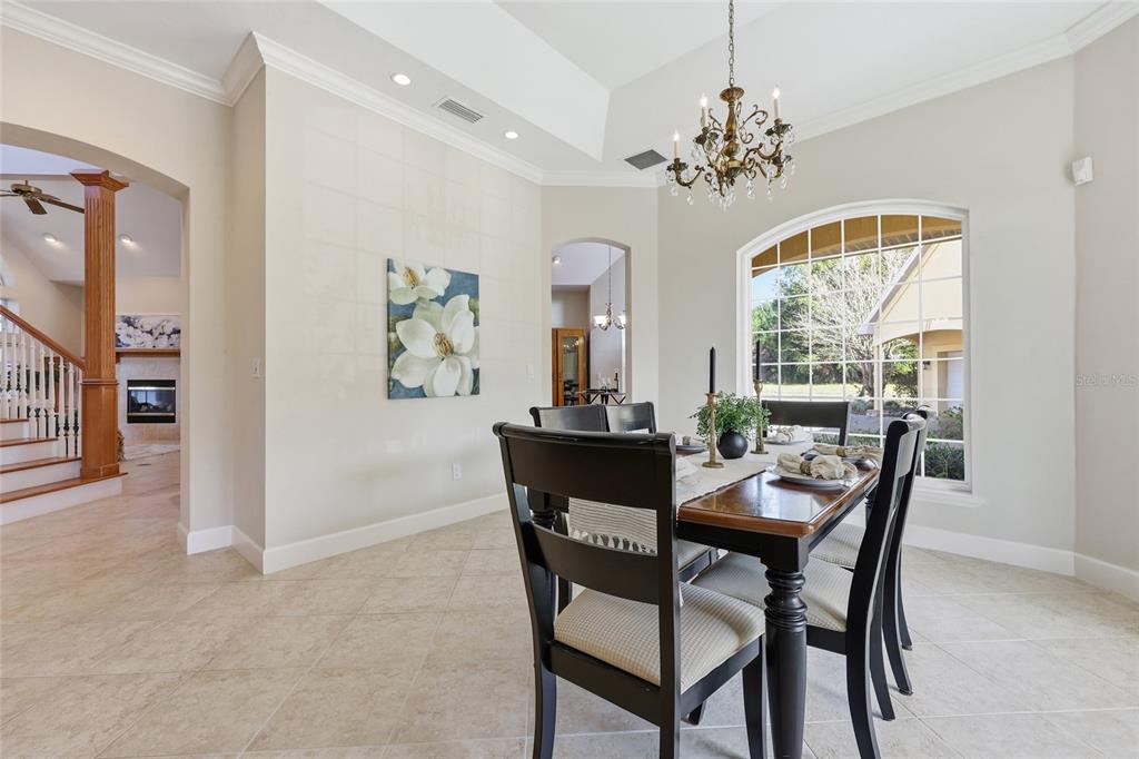 A dining room features a dark wood table, chandelier, tile floors, and a large arched window — 18604 NW 262 AVENUE, ALACHUA, FL