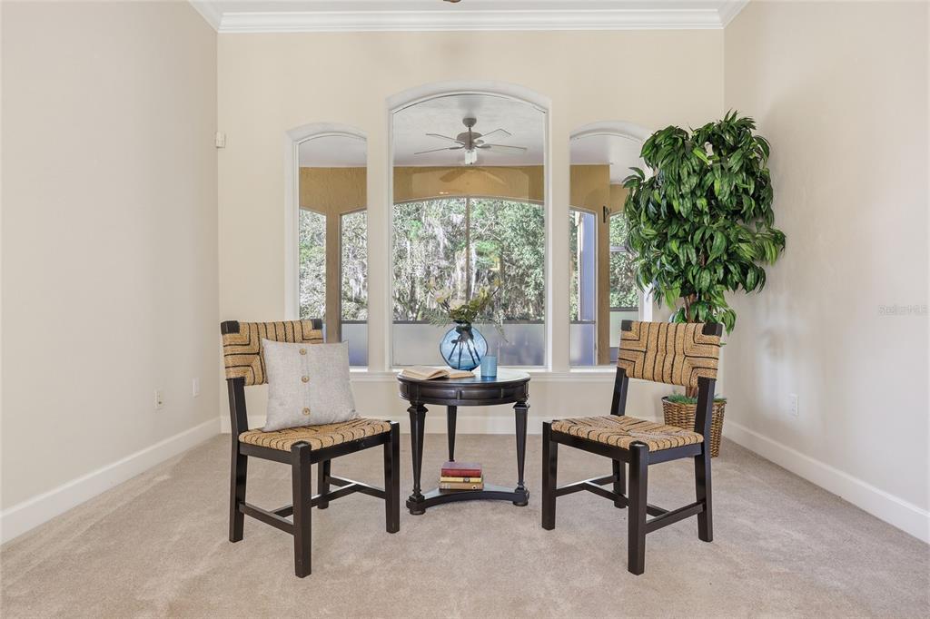 A carpeted sitting area features two woven chairs, a small round table, and arched windows — 18604 NW 262 AVENUE, ALACHUA, FL