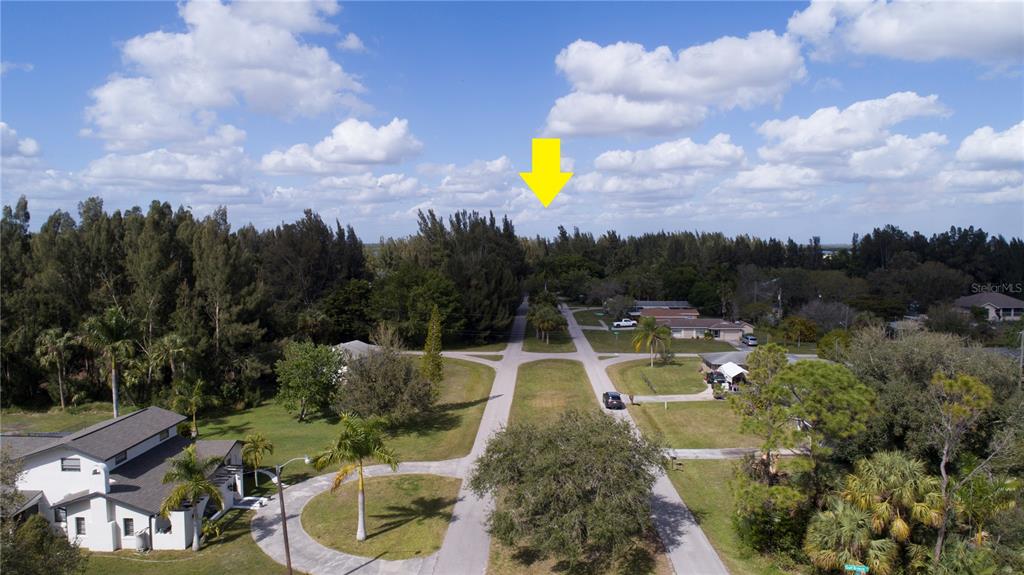 An aerial view shows a residential street intersection surrounded by trees and houses — 418 PEACE ISLAND DR, PUNTA GORDA, FL