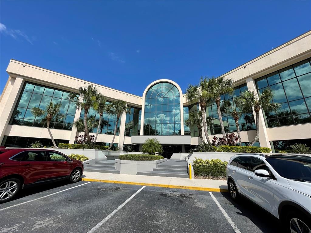 A multi-story commercial building with a glass facade and palm trees in the parking lot — 1300 CITIZENS BOULEVARD, LEESBURG, FL